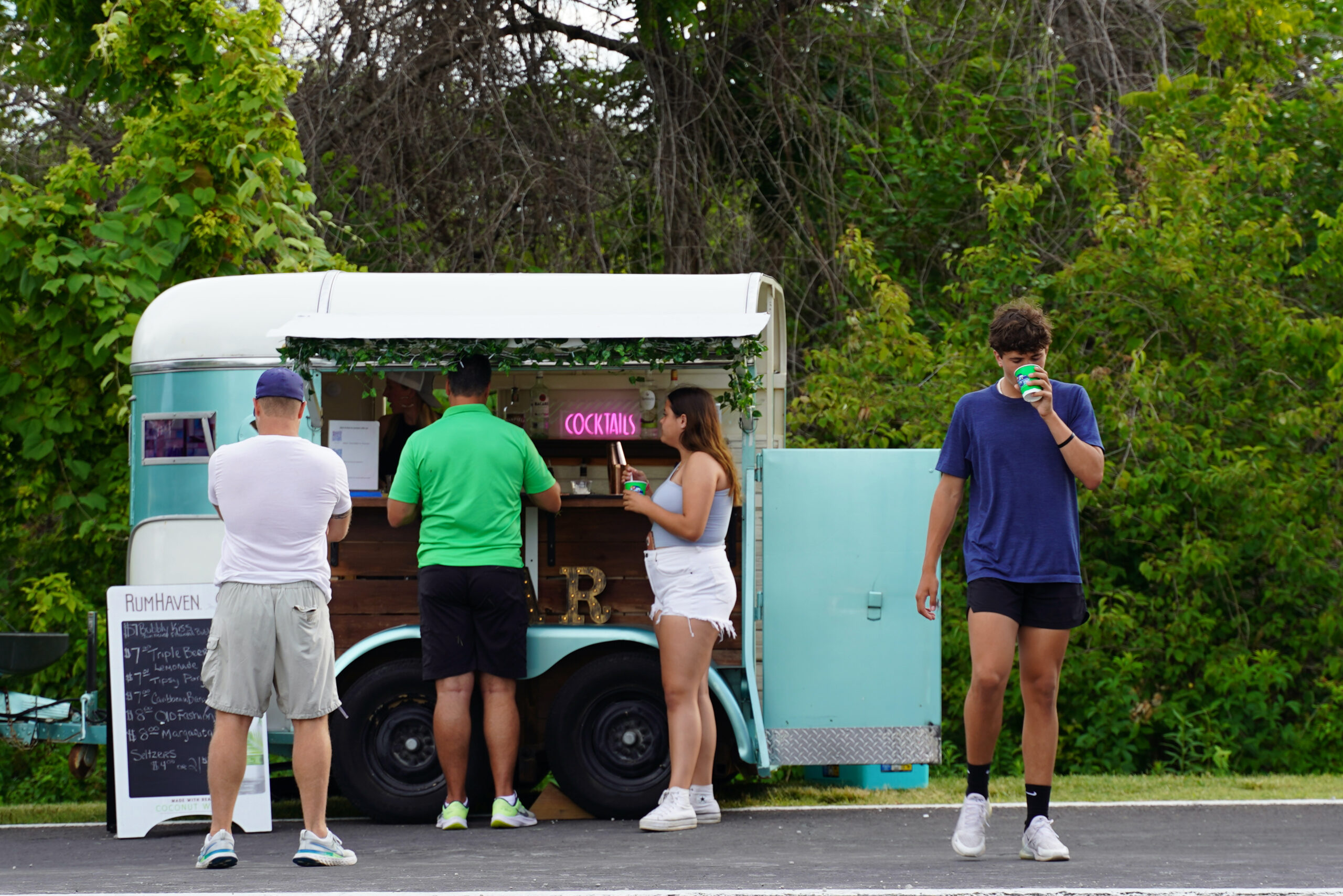 People standing around a light blue food truck.
